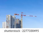 Tower cranes on the construction site of a block of flats of the monolithic residential apartment building