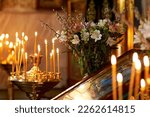 Small photo of Palm Sunday. candles burn in an Orthodox church in front of the icon, against the background of willow and flowers
