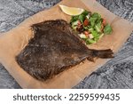 Small photo of Flounder baked with garlic and vegetables. Fried flounder. Seafood. Gray background.