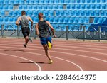 back two decathlon athletes running sprint race track, summer athletics championships at stadium