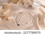 Small photo of Pearl silver necklace on silk background - Pearl handmade jewelry top view