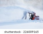 man with a snow blowing machine working in winter day