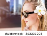 Beautiful woman in black sunglasses from Prada poses  with white flower in her hair