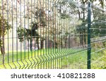 Green wire fence on background of green trees