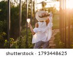 Young beautiful woman hipster drinking wine in vineyard at sunset on summer sunny day.