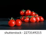bunch of fresh cherry tomatoes with green stems isolated on dark grey marble table