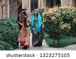 Small photo of Beautiful azeri women in traditional Azerbaijani dress running by the wooden door of an old house. Spring, Novruz holiday celebration concept