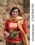 Small photo of Young azeri woman in traditional Azerbaijani clothes, haystacks on background. Beautiful muslim woman, outdoors portrait