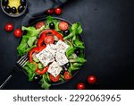 Greek salad with feta cheese, olives, cherry tomato, paprika, cucumber and red onion, healthy vegetarian mediterranean diet food, low calories eating. Black stone background, top view, copy space