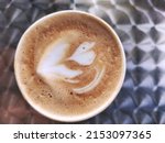 Small photo of Close-up of cappuccino coffee foam. Isolated over metal pattern background. Top view. Black cappuccino coffee with heady froth in a glass mug or cup. Close-up shot of barista coffee cup