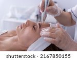 Small photo of close up of Cosmetologist,beautician applying facial dermapen treatment on face of young woman customer in beauty salon.Cosmetology and professional skin care, face rejuvenation.