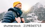 Small photo of Winter hike on snow mountain young happy hiker man climbing. Europe travel adventure trek in nature landscape. Young cheerful person wearing yellow hat, blue jacket for cold weather and bag.
