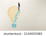 European woman in suit standing on abstract pattern light bulb on light background with mock up place. Idea, growth and success concept