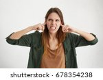 Agressive female plugging her ears being angry with her neighbours who are very noisy. Irritated beautiful young woman trying to avoide loud sounds from house next door hating creaking sounds