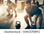Fit young man in sportswear focused on lifting a dumbbell during an exercise class in a gym