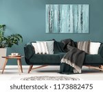 Patterned cushions on sofa next to wooden table and plant in dark apartment interior. Real photo