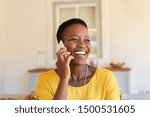 Smiling african american woman talking on the phone. Mature black woman in conversation using mobile phone while laughing. Young cheerful lady having fun during a funny conversation call.