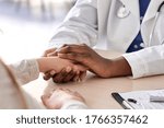 Small photo of African female doctor hold hand of caucasian woman patient give comfort, express health care sympathy, medical help trust support encourage reassure infertile patient at medical visit, closeup view.