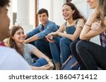 Group of happy young friends sitting in college campus and talking. Cheerful group of  smiling girls and guys feeling relaxed after university exam. Excited millenials laughing and having fun outdoor.