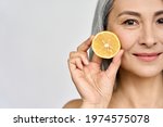 Beauty. Closeup portrait of middle aged beautiful Asian 50s woman with perfect natural makeup holding citrus juicy lemon fruit. Vitamin C cosmetics whitening treatment advertising concept. Copy space.