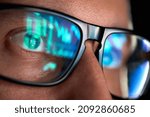 Focused crypto trader analyst wearing eyeglasses working looking at computer screen reflecting in glasses analyzing online trading stock exchange market data charts. Close up eye reflection.