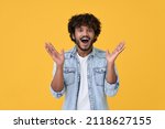 Amazed excited young indian man looking at camera with wow face expression feeling surprised advertising shopping promotion, unbelievable betting win standing isolated on yellow background.