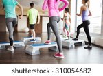 Small photo of fitness, sport, training, aerobics and people concept - close up of people working out with steppers in gym from back