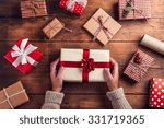 Man holding Christmas presents laid on a wooden table background