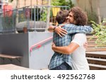 Cheerful best friends embracing each other outside coffee shop. Two young multiethnic guys hugging each other. Happy smiling best friends meeting each other after a long time with a hug.