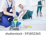 Professional interior construction worker pouring green color to paint
