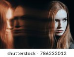 Young girl with personality disorder against black background with blurred face