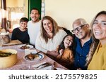 Happy latin family having fun eating together home - Focus on grandmother face
