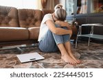 Small photo of Sad woman sits on floor near scales and holding her knees by hands. Problem of weight change and unattainable wishes regarding body shape.