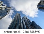 Blue sky with clouds framed by sleek modern glass high rise buildings