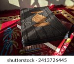 Small photo of Yogyakarta, Indonesia - December 21, 2023 : Holy Quran with written arabic calligraphy meaning of Al Quran and beads or tasbih. Wrote on it "Al Quran Al Karim" in Arabic. Islamic concept