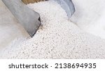 Small photo of White secondary processing plastic granule comes out of the granulator crusher into small granules. Concept of plastic recycling, production of secondary raw materials. White Plastic pellets crumbles