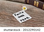 Small photo of Faith over fear. Inspiring handwritten quote from the Bible Book. Trust, faith, hope, belief in God and Jesus Christ. Devoted faithful Christian biblical concept. A closeup.