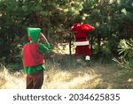 Small photo of Cute boy elf declassified Santa Claus with a bag of gifts in the woods among the Christmas trees, Santa found, the end of the holiday Christmas and New Year