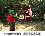 Small photo of Cute boy elf declassified Santa Claus with a bag of gifts in the woods among the Christmas trees, Santa found, the end of the holiday Christmas and New Year