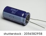 Small photo of Electrolytic capacitor is an electronic component that function to temporarily store electric current. Blue electronic capacitor with polarity on white background isolated. Macro closeup shots.