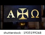 Small photo of black metal panel with the Greek cross and the letters alpha and omega in gold, symbol of the beginning and the end in Christianity, in the Monastery of Leyre