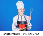 Small photo of Very easy to use. Professional cook smiling with pot and wire whisk. Cute kitchen maid with stainless steel whisk and mixing bowl. Happy cook holding balloon whisk and cooker.
