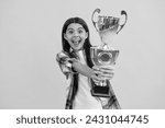 Small photo of proud teen girl with champion cup award, selective focus. teen girl hold her award champion cup isolated on yellow. teen girl receive award in studio. teen girl accept award on background
