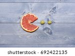 Small photo of Packman theme composition of grapefruit and grapes. Art and healthy food concept. Tasty snack with summer fruit, top view. Food on vintage background.