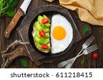 Fried Egg in pan and vegan avocado sandwiches top view close-up in rustic style on a wooden background, cutting boards, forks, knife, arugula, concept of a healthy lifestyle