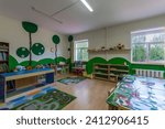 Small photo of A kindergarten playroom with drawings on the walls and lockers with books and toys.