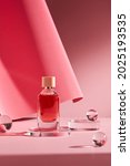 Small photo of Abstract background for branding and minimal presentation. Cosmetic bottle on pink podium, on folding paper pleated geometric background with glass ball.