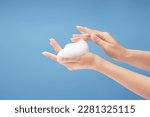Small photo of Over a light blue background, a beautiful woman's hands are adorned with white foam mousse. Daily self care routine concept