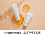 Laboratory concept with orange liquid contained inside of spiral pipe tube and glass petri dishes. Empty label white tubes for cosmetic product promotion