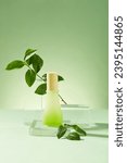 Small photo of A label-free cosmetic bottle takes center stage on a glass platform, surrounded by vibrant green tea leaves-a homemade cosmetics concept enriched with green tea extract on pastel background.